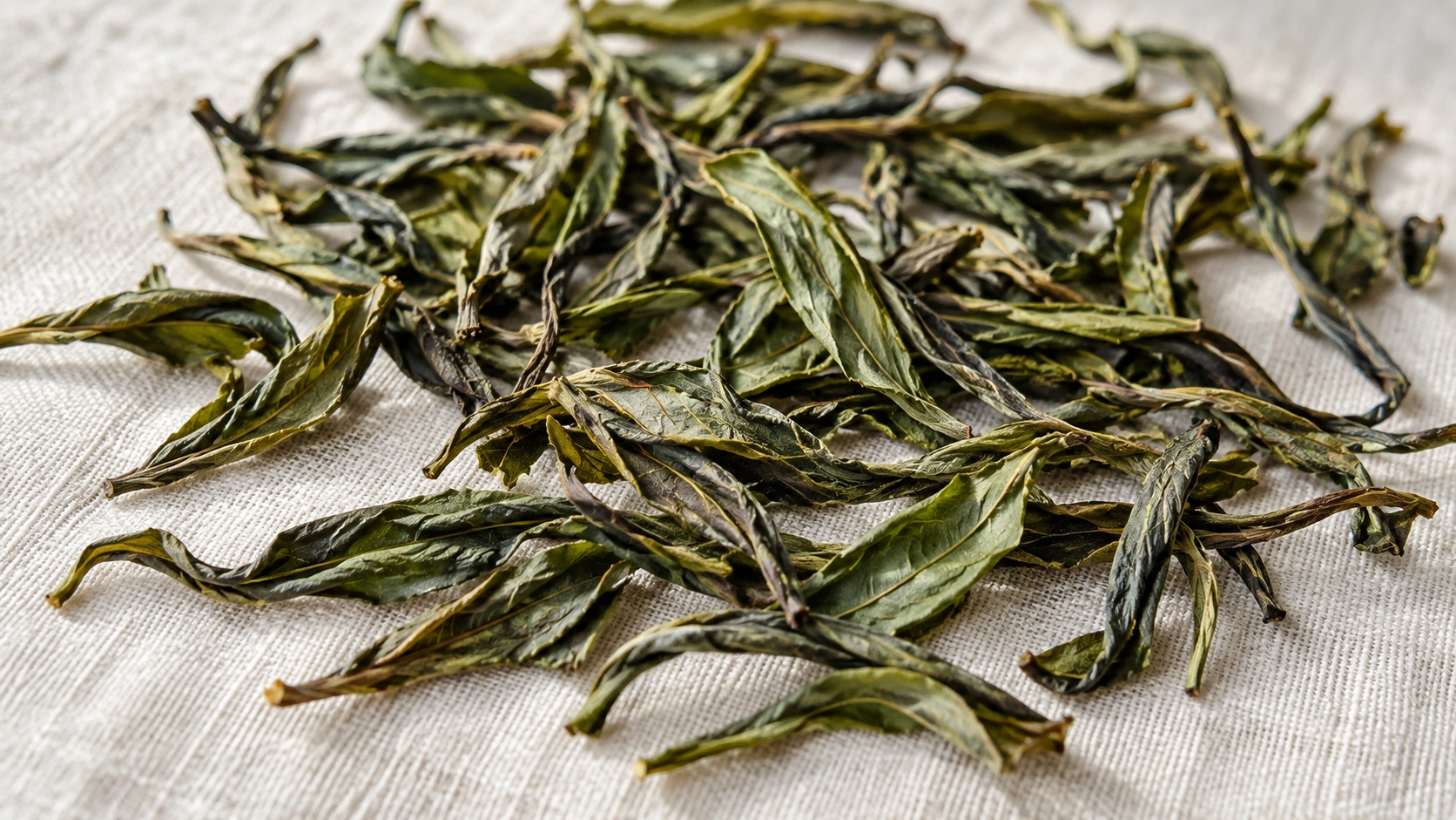 AI-generated editorial illustration: Long curled dry green tea leaves spread on linen; Baozhong cultivar and origin unverified