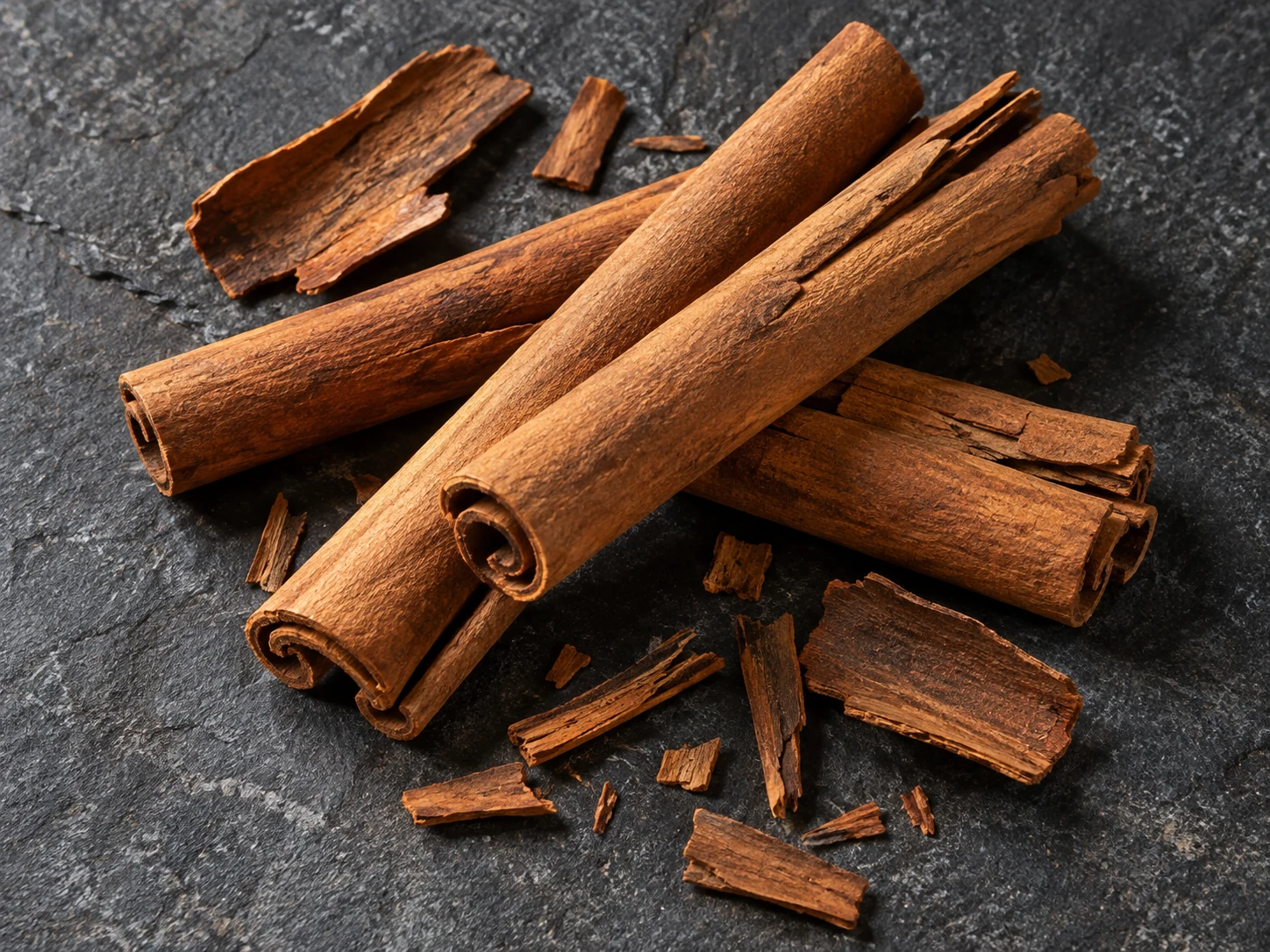 AI-generated editorial photograph of cinnamon bark quills and curled sticks scattered on dark stone