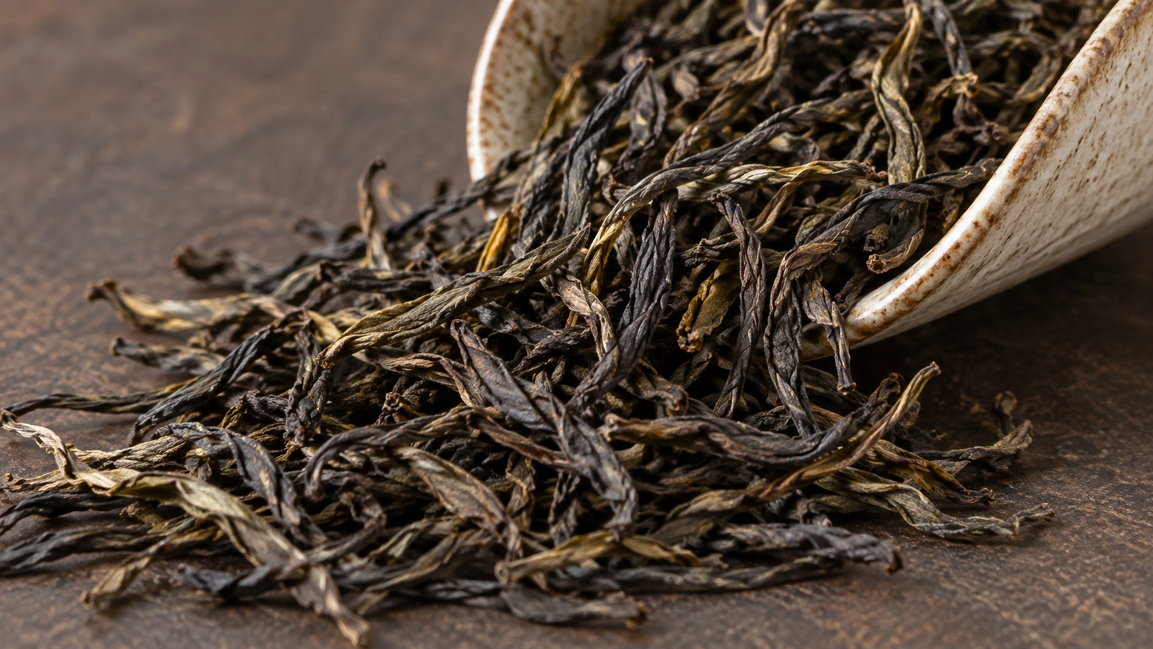 AI-generated editorial image: Twisted, dark loose oolong-style tea leaves poured onto stone